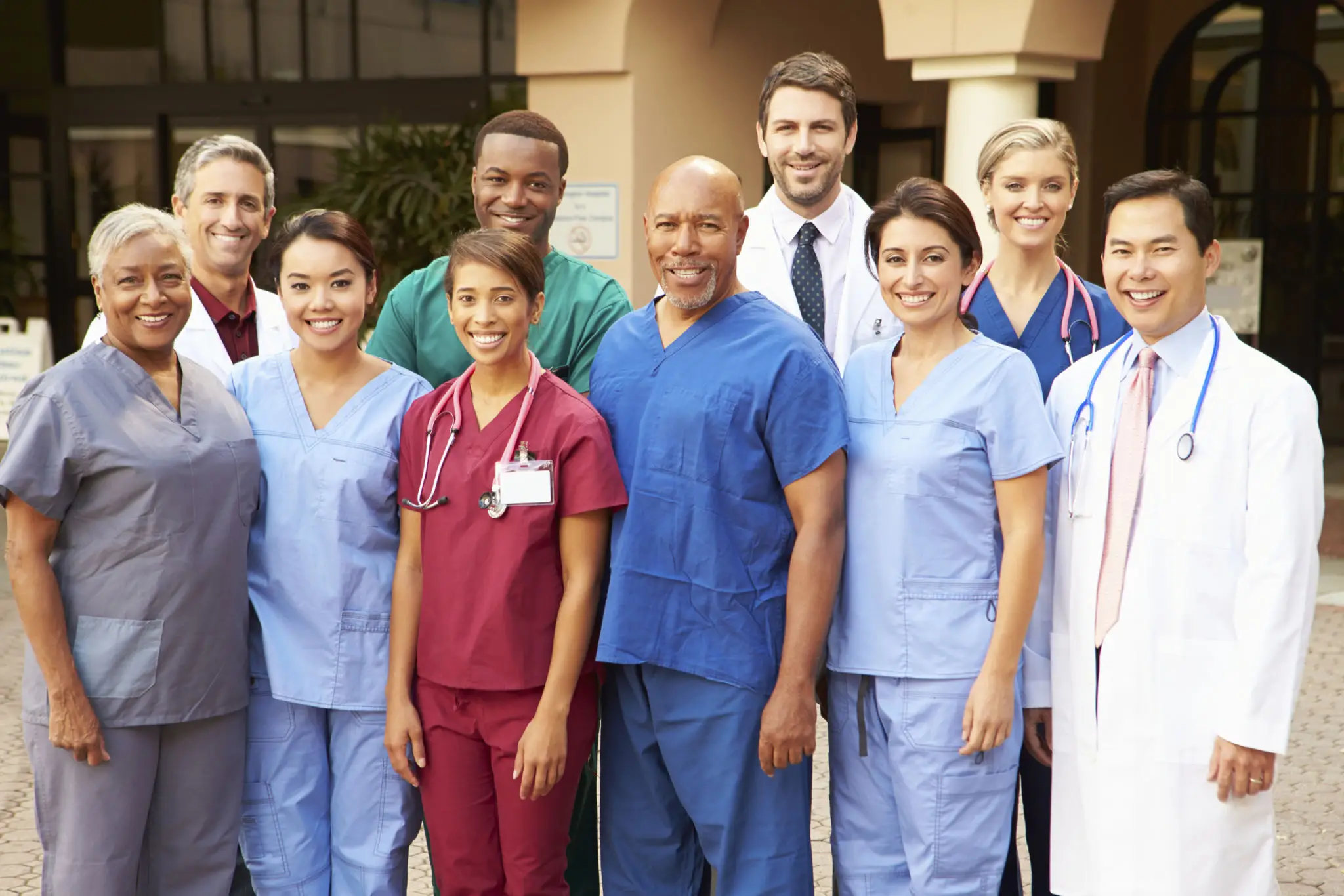 Group of diverse healthcare professionals posing together in scrubs.