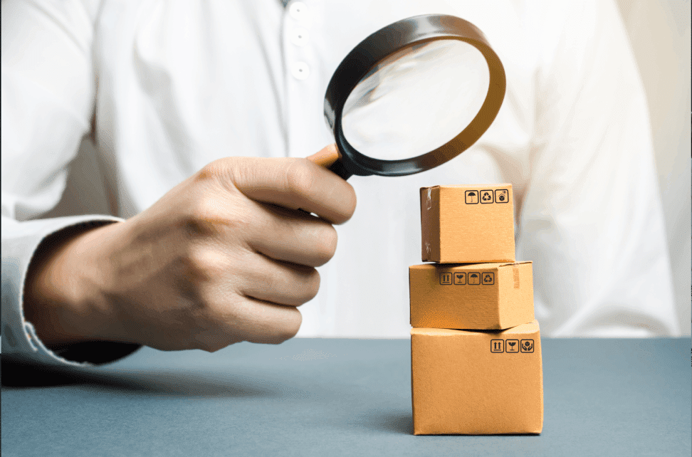 Person inspecting boxes with magnifying glass.